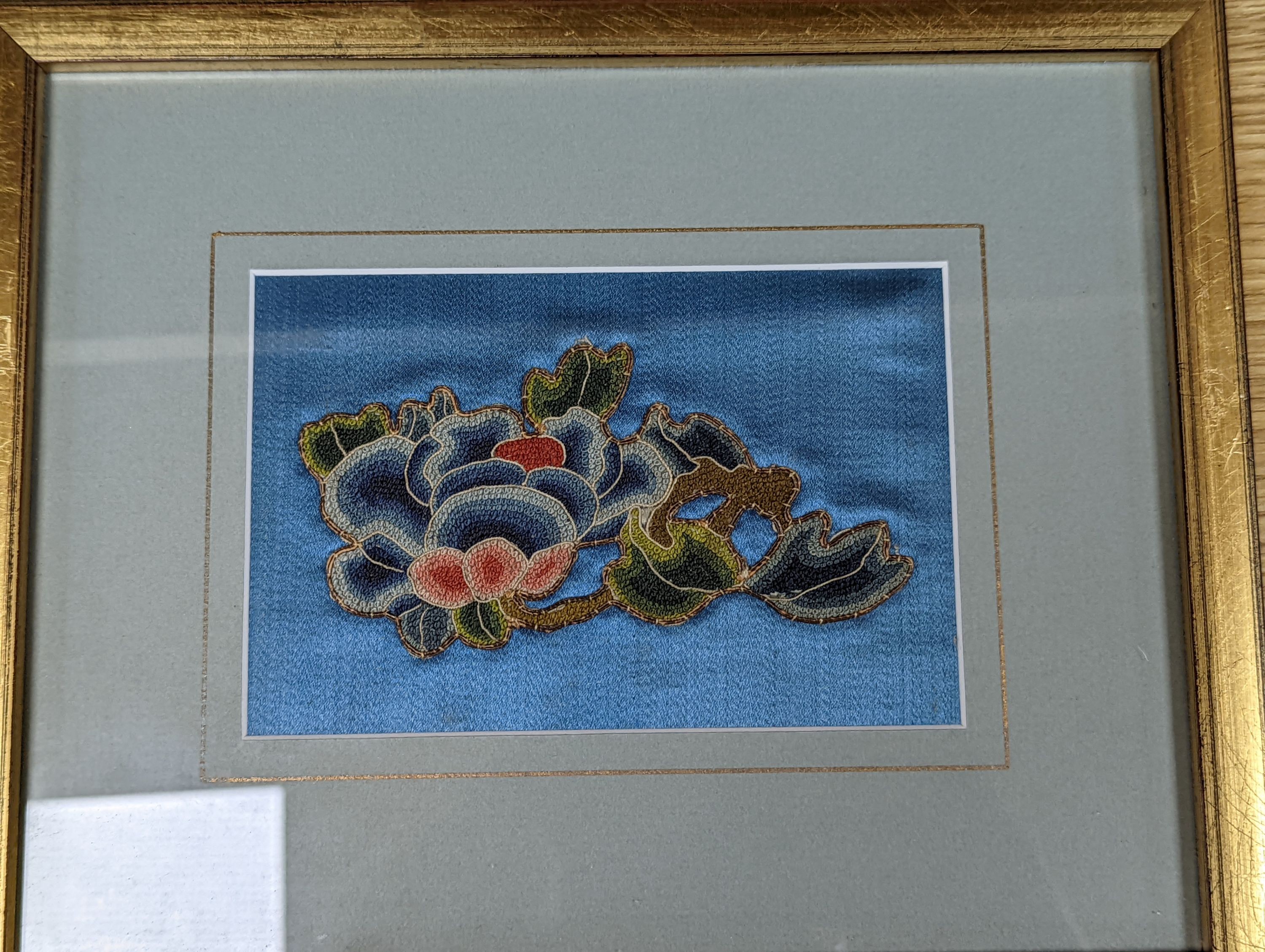 A set of four Chinese silk embroidered motifs, a pair of floral silk motifs and a later pair f sleeve bands, all framed
